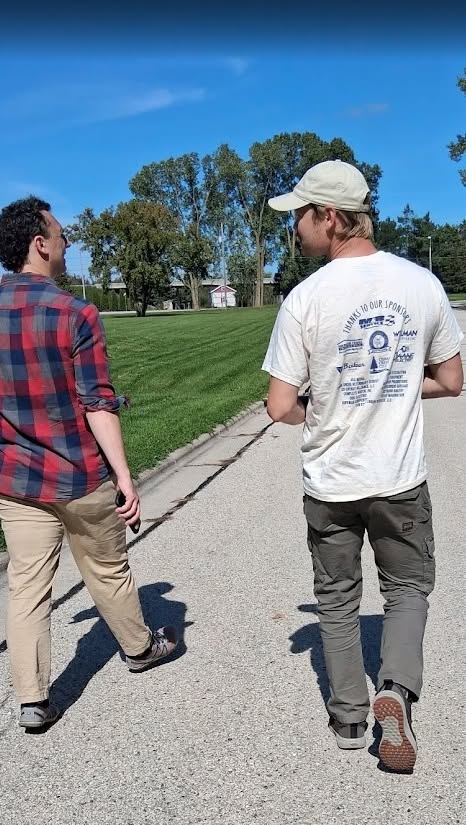 Two volunteers walk along a neighborhood street while canvassing for Tom Tiffany.